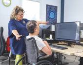 Persona con disabilità davanti al computer assistita da un'operatrice