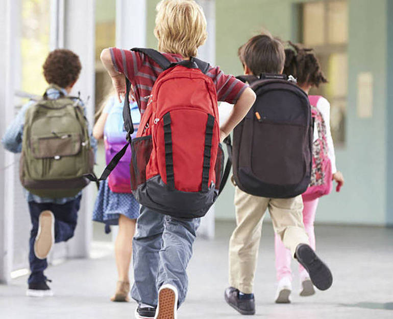 Bambini con la zainetto a spalle corrono nel corridoio di un istituto scolastico Bambini con la zainetto a spalle corrono nel corridoio di un istituto scolastico