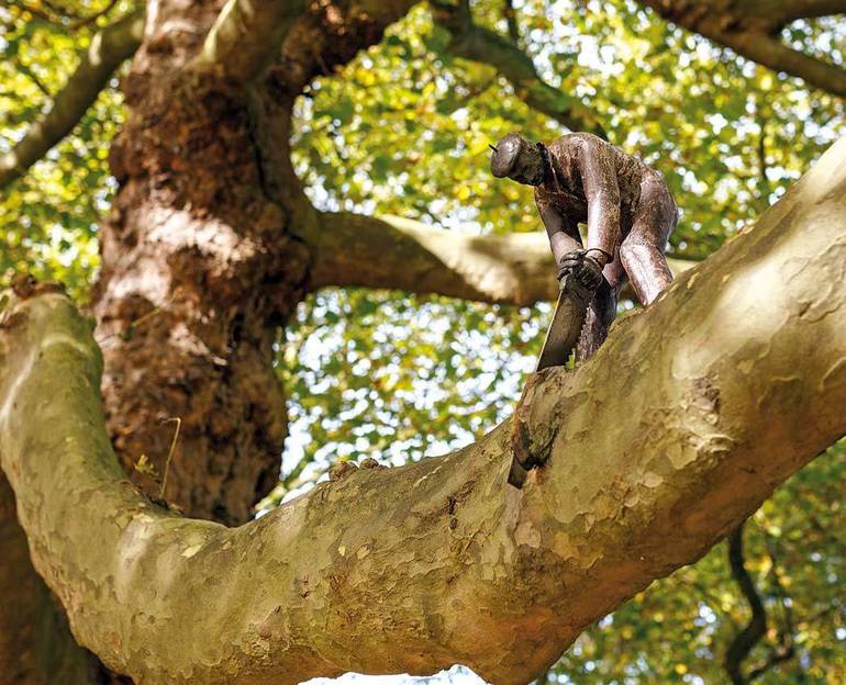 Uomo che taglia il ramo (scultura moderna nel parco pubblico della città di Amsterdam)