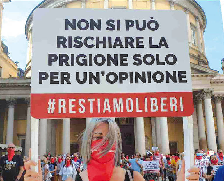 Manifestante in primo piano che regge un cartello con su scritto: "Non si può rischiare la prigione solo per u n'opinione. #restiamoliberi" Manifestante in primo piano che regge un cartello con su scritto: "Non si può rischiare la prigione solo per u n'opinione. #restiamoliberi"