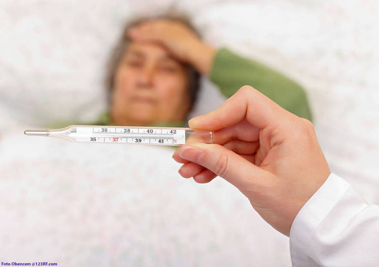 Termometro per a febbre con sfondo di influenzata persona a letto (Foto Obencem @123RF.com)