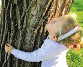 Bambina, in primo piano, che abbraccia un albero