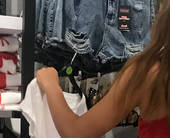 Giovane donna in un negozio di abiti osserva da vicino un . capo di abbigliamento