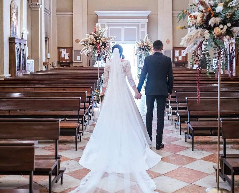Immagine di due sposi ripresi di spalle che escono dalla chiesa vuota al termine del rito del matrimonio Immagine di due sposi ripresi di spalle che escono dalla chiesa vuota al termine del rito del matrimonio
