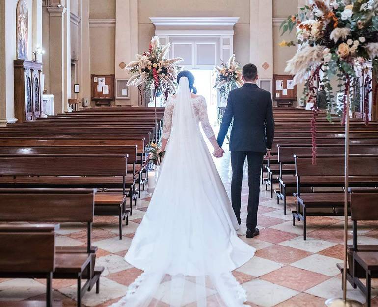 Immagine di due sposi ripresi di spalle che escono dalla chiesa vuota al termine del rito del matrimonio