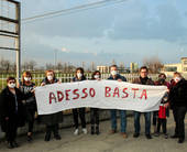 Persone con mascherina alla boca cge reggono unoscriscione con scritto: "Adesso basta"