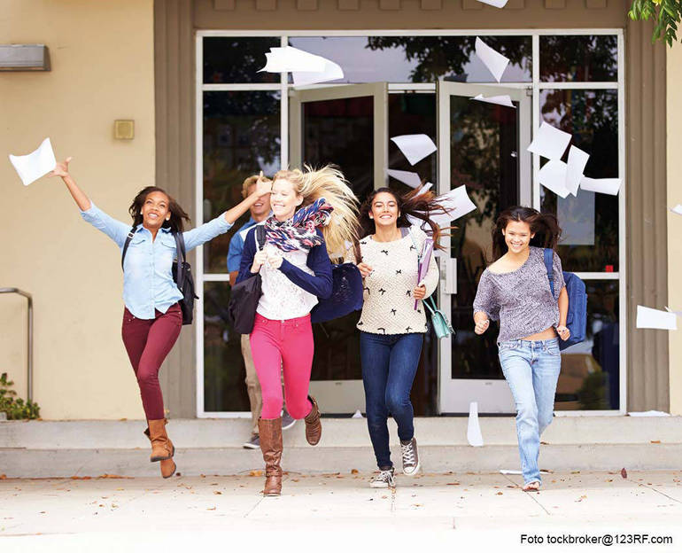 Studentesse felici che corrono all'uscita dalla scuola con foglietti svolazzanti (Foto Stockbroker@123RF.com)