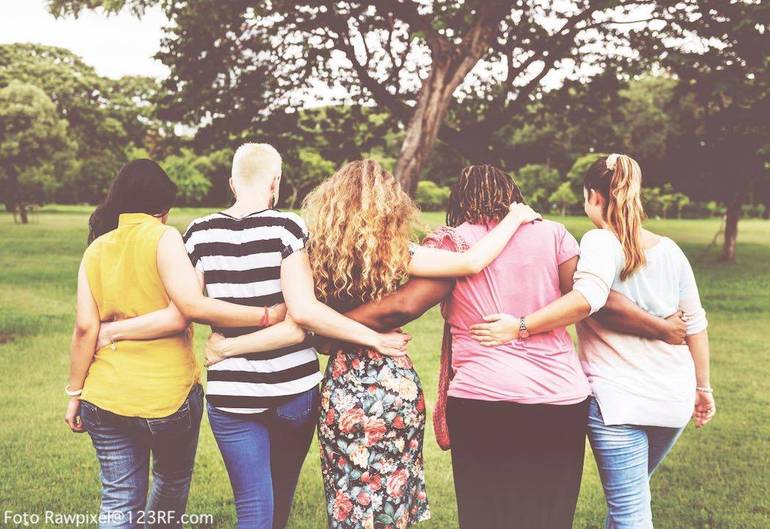 Cinque donne riprese di spalle che camminano nel verde tenendosi abbracciate (Foto Rawpixel@123RF.com)