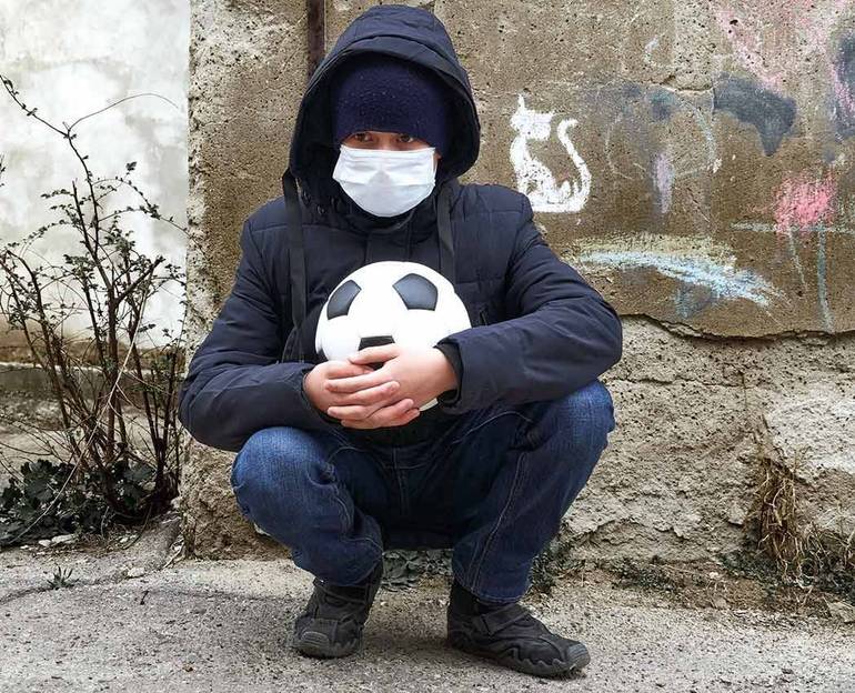 Bambino con pallone e mascherina da solo, accosciato (foto Soleg@123RF.com)