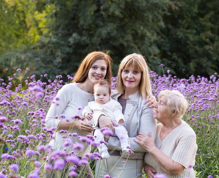 Immagine di 4 donne in un campo fiorito, la nonna, la mamma, la figlia e la nipotina