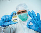 Operatore sanitario bardato con falcone del vaccino in mano e simbolo di OK con l'altra