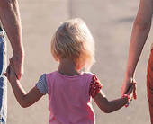 Bambina di spalle tenuta per mano dai genitori