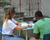 Una volontaria aiuta un ragazzo straniero a studiare la lingua italiana