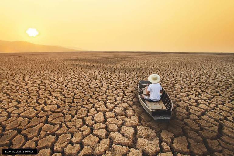 Una persona in barca sta remando su un "mare" di terra inaridita