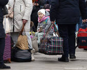persone con bagagli in partenza con primo piano di un bambino dallo sguardo preoccupato