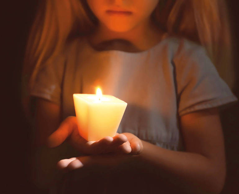 Bambina che tiene un lume acceso nel buio