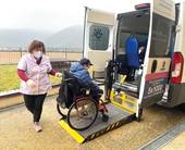 Operatore aiuta persona con disabilità in carrozzina a salire su un pulmino attrezzato
