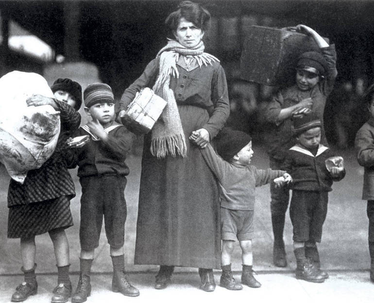 Immagine d'epoca di una famiglia di immigrati con una donna e bambini con le valigie