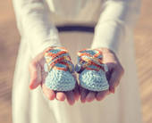 Due mani presentano delle scarpine da neonato