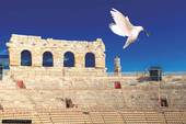 Sullo sfondo delle gradinate dell'anfiteatro areniano una colomba in volo con un ramoscello d'olivo, simbolo della. pace
